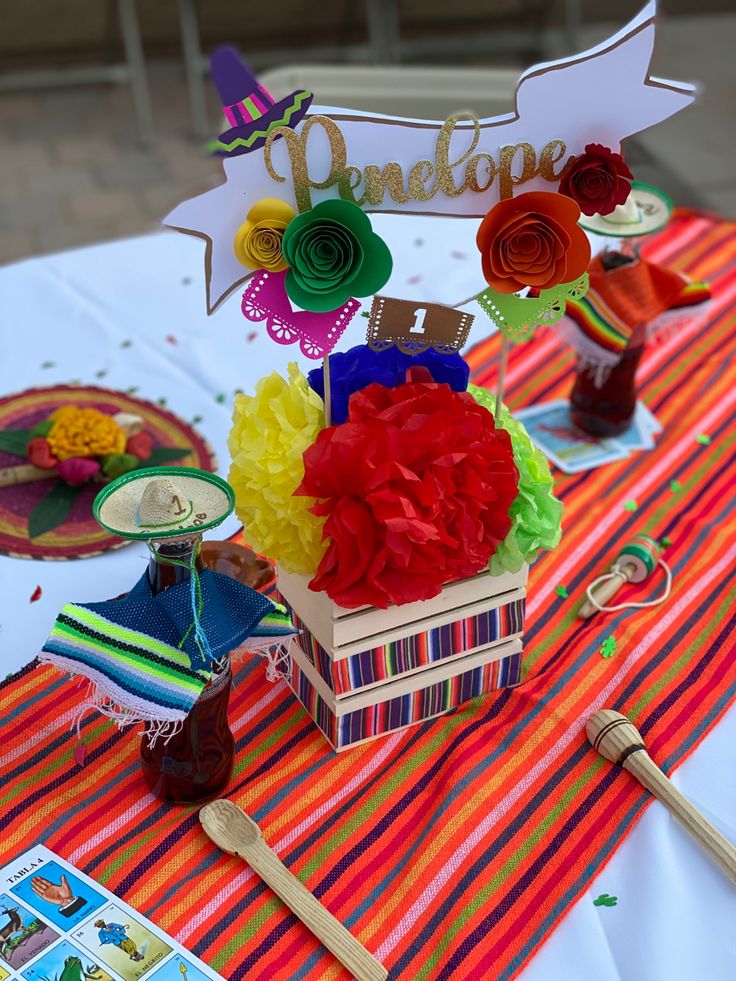 a table topped with lots of colorful flowers and paper decorations on top of it's sides