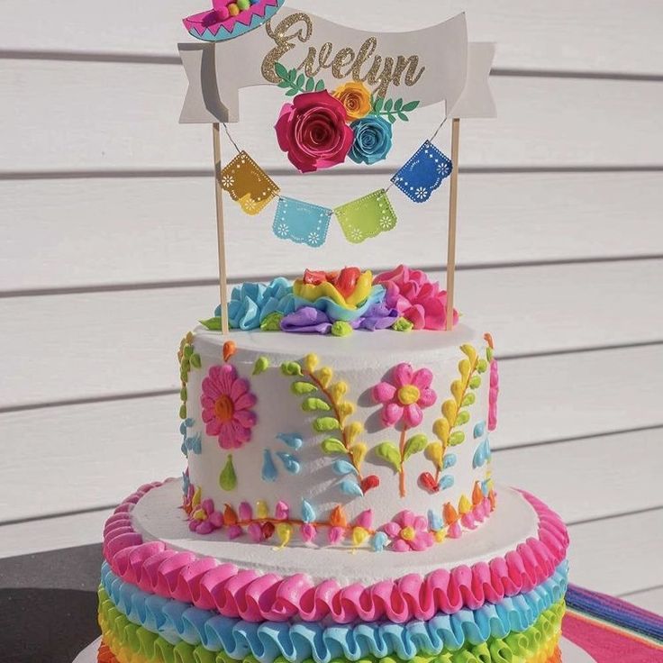 a multi layer cake decorated with flowers and bunting