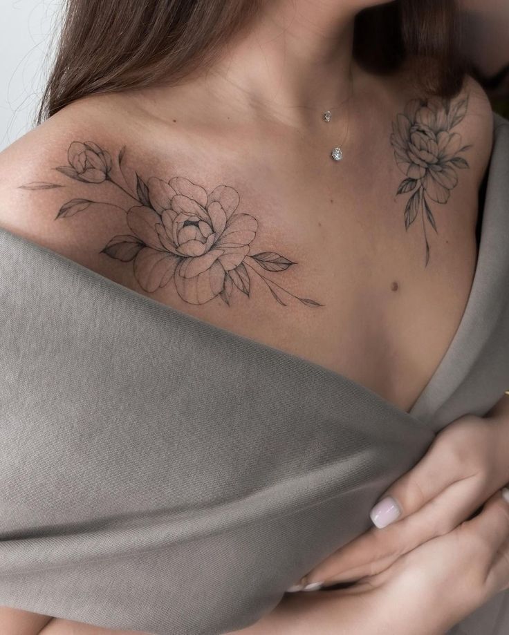 a woman with a flower tattoo on her chest holding a piece of fabric over her shoulder