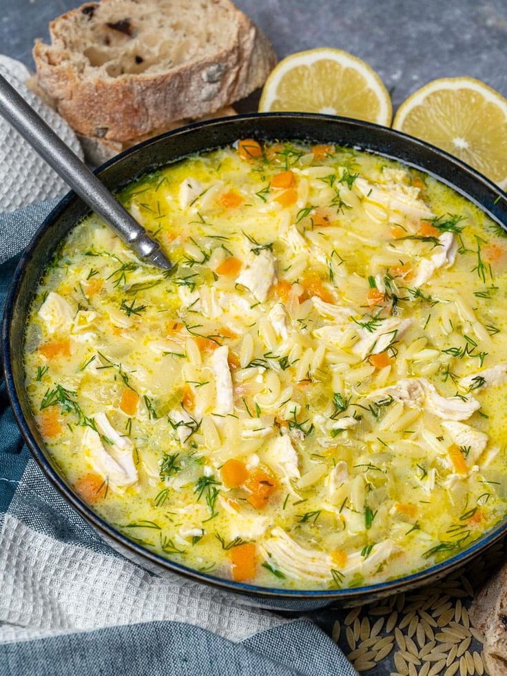 a bowl of soup with bread and lemon slices