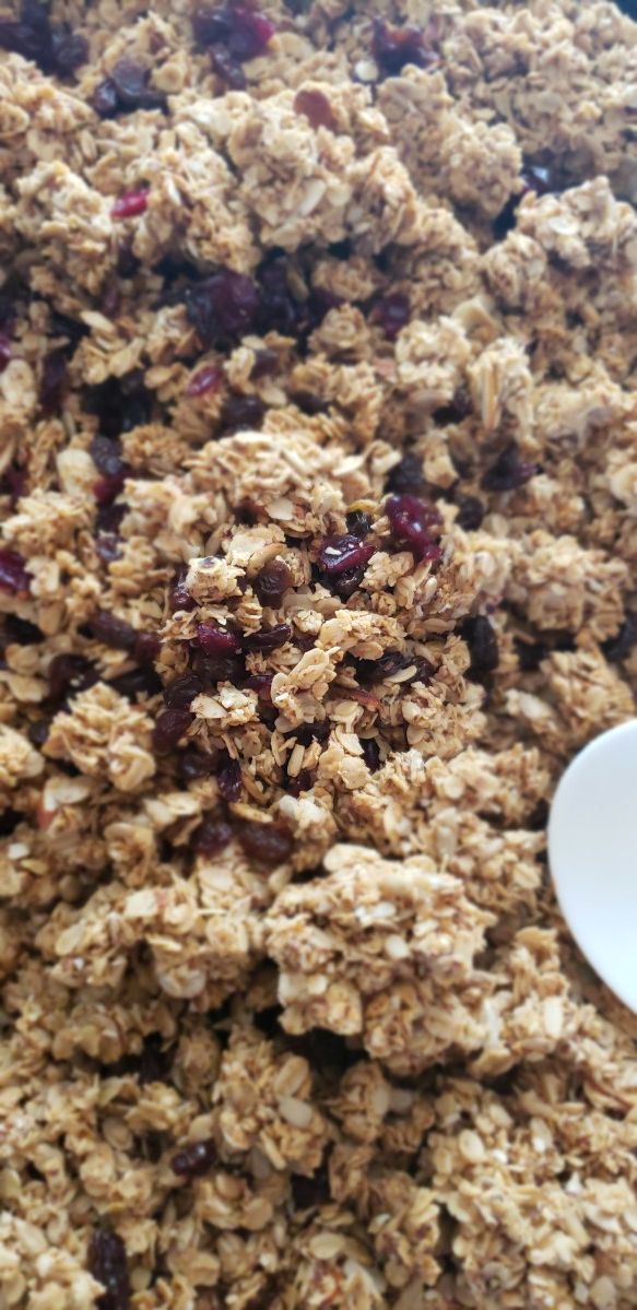 granola with raisins and cranberries in a bowl next to a spoon