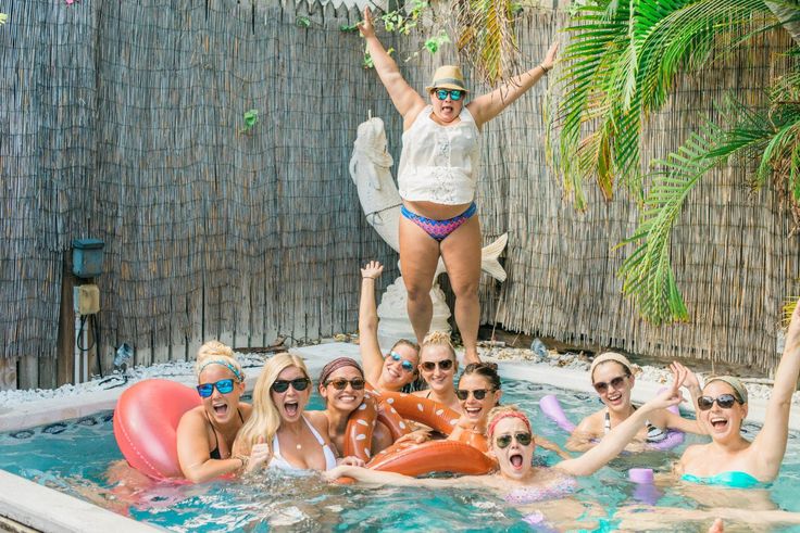 a group of people in a swimming pool posing for the camera with their arms up