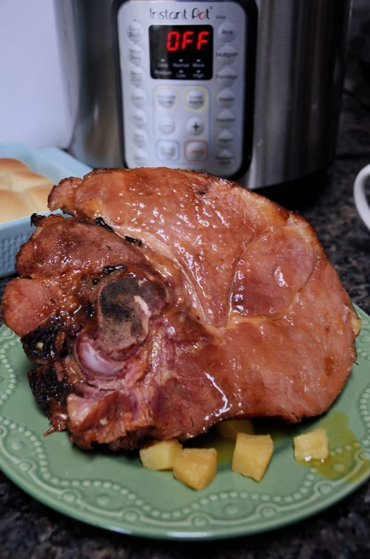 a green plate topped with meat and potatoes next to an instant pot roaster oven