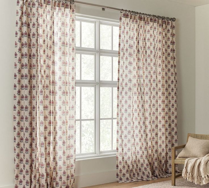 a living room with white walls and curtains on the window sill, along with a chair