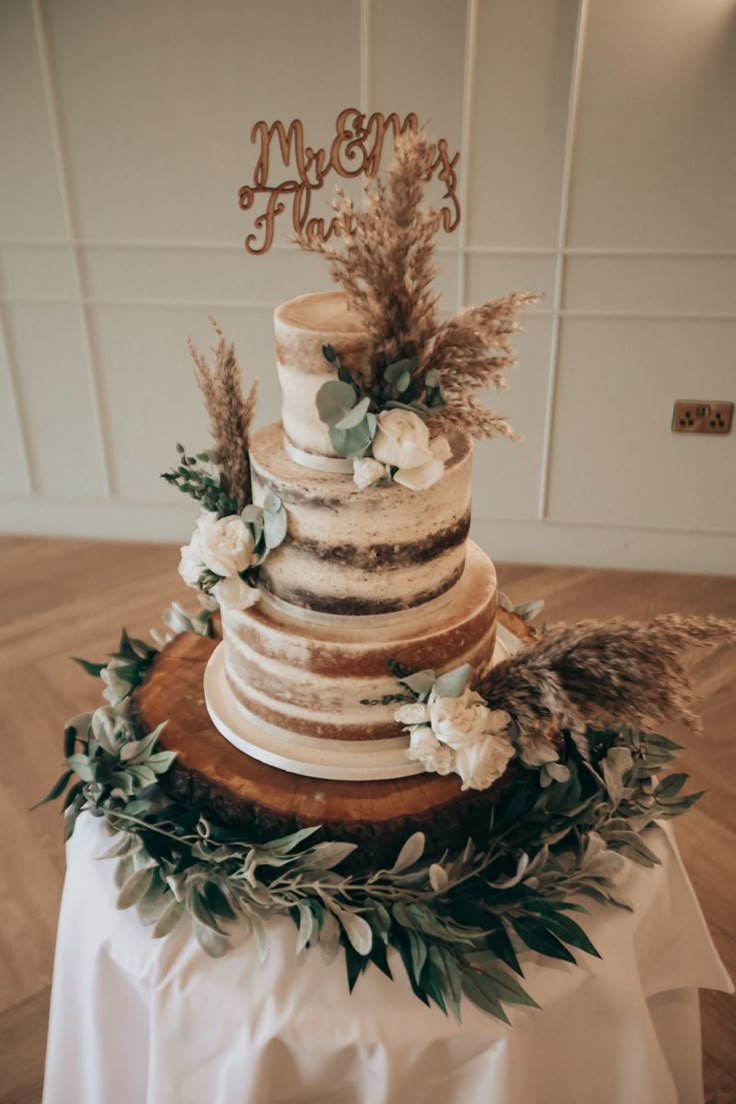 a wedding cake with flowers and greenery on top