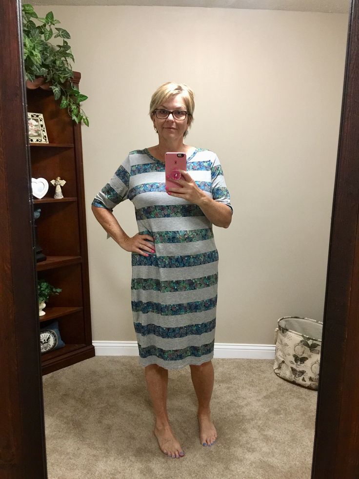 a woman standing in front of a mirror taking a selfie with her cell phone