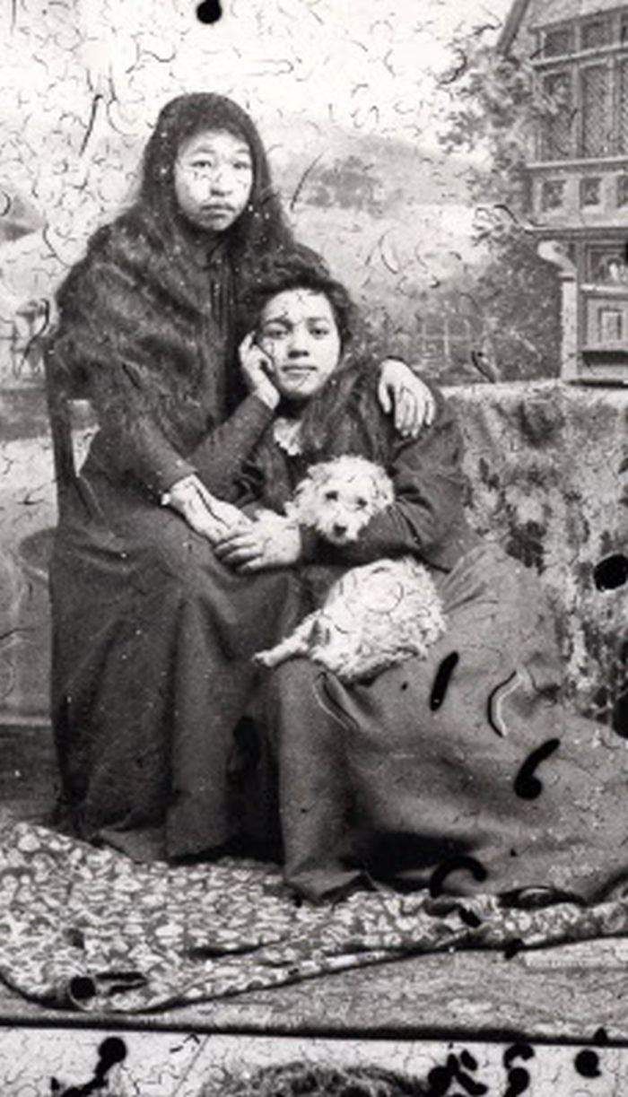 an old photo of two women and a dog