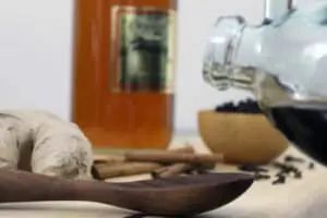 a dog laying down next to a glass of wine and some cinnamon sticks on a table