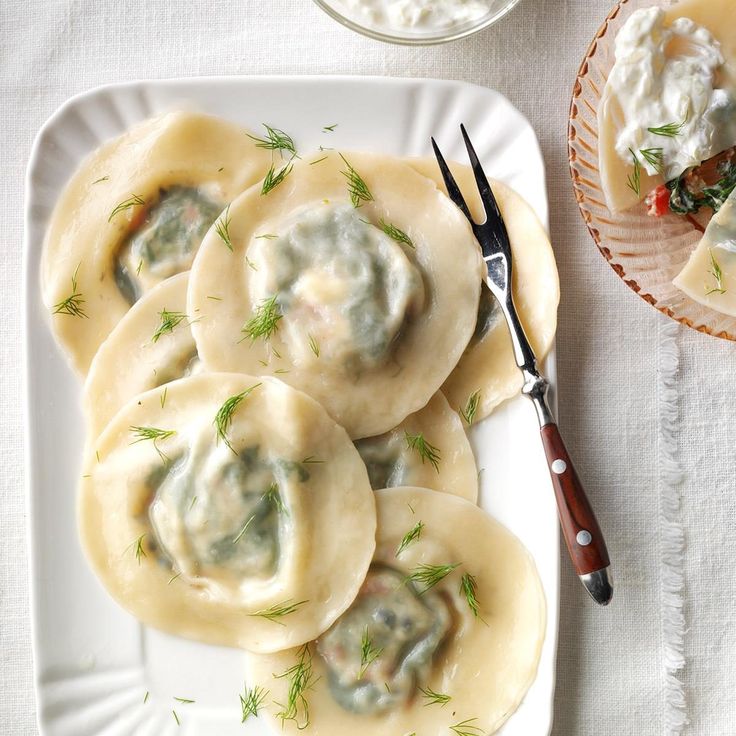 some dumplings are sitting on a plate with sauce and a fork next to them