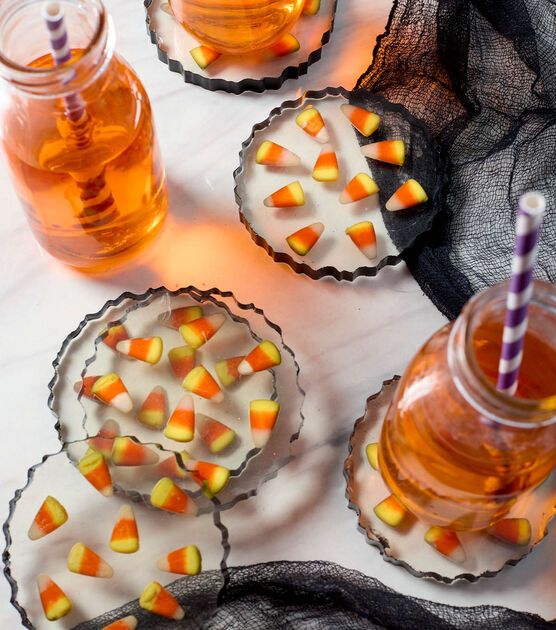 halloween desserts with candy on the top and candles in glass jars next to them