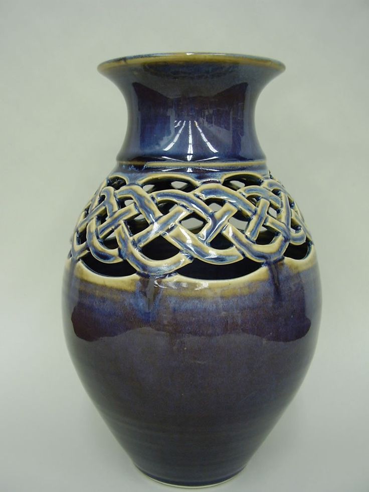 a blue and brown vase with an intricate design on the top, sitting on a white surface