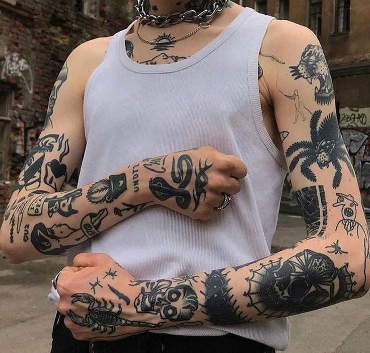 a man with many tattoos on his arms and arm is standing in front of a building