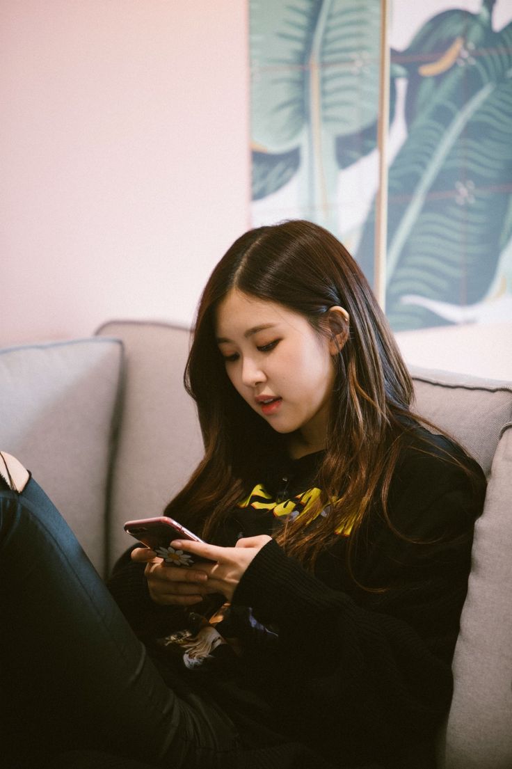 a woman sitting on a couch looking at her cell phone