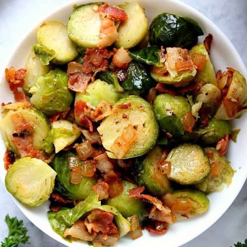 a white bowl filled with brussel sprouts and bacon