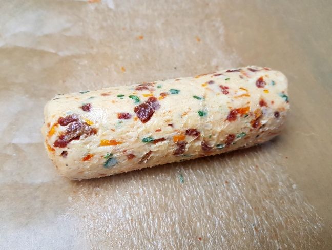 a piece of food that is on top of some wax paper and has sprinkles all over it