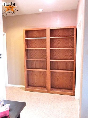 an empty room with two wooden bookshelves in it