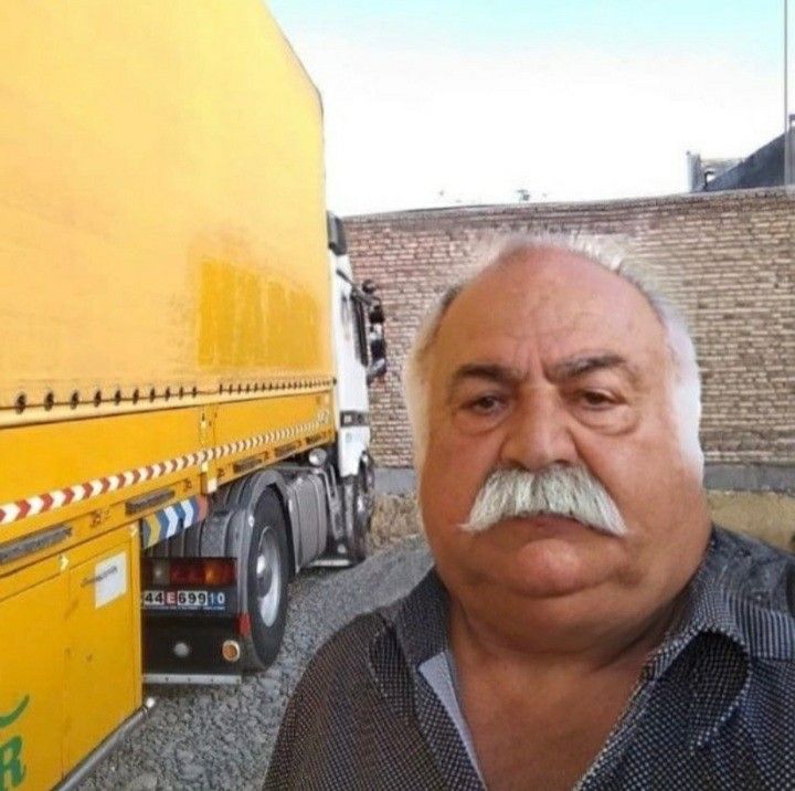 a man with a mustache standing in front of a yellow truck