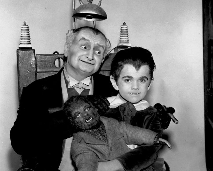 an old black and white photo of two men with creepy faces, one holding a doll