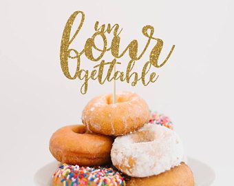 a white plate topped with donuts covered in sprinkles and a gold cake topper