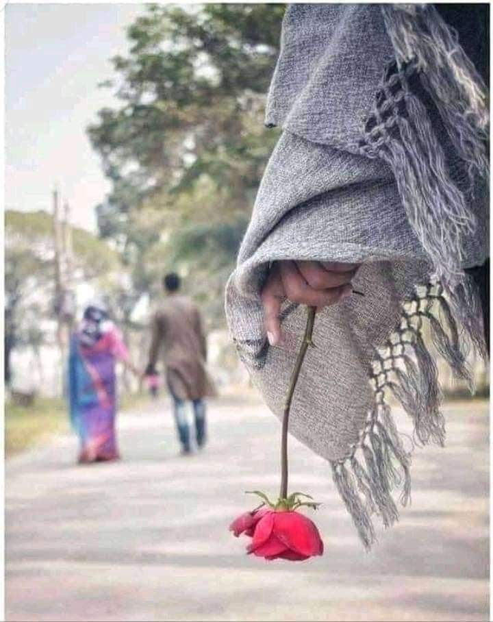 a person holding a flower in their hand while walking down the street with other people behind them