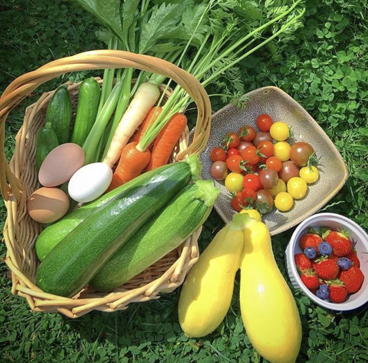 a basket filled with lots of different types of fruits and vegetables next to some eggs