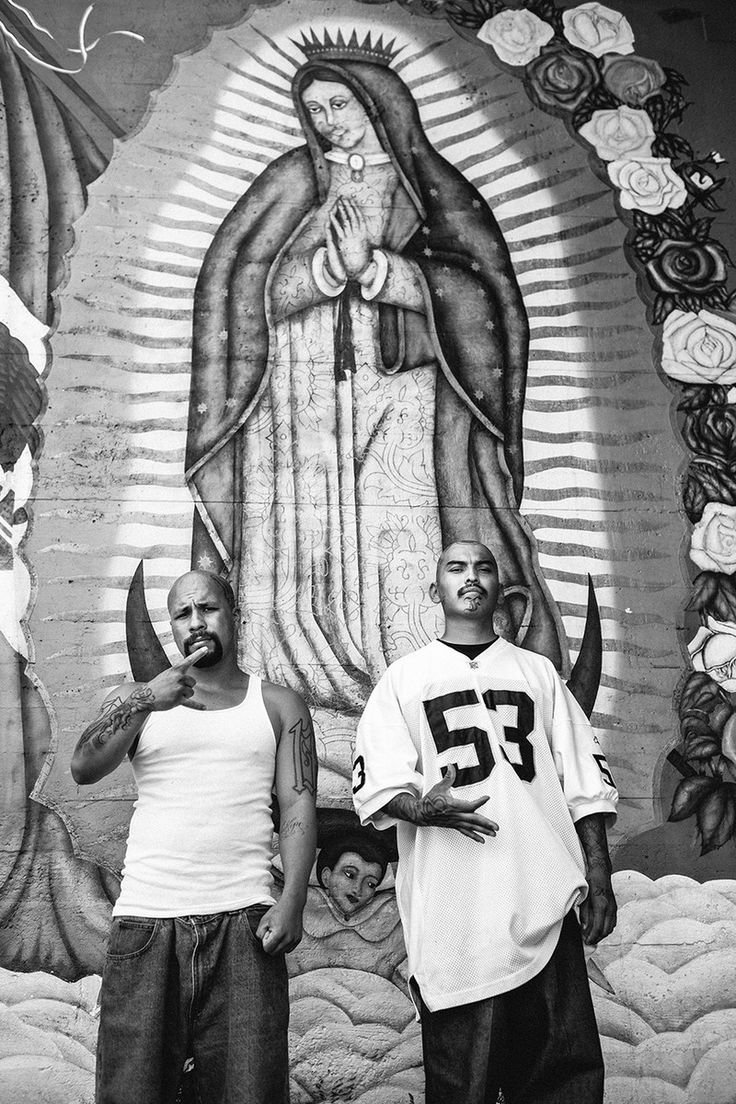 two men standing next to each other in front of a mural