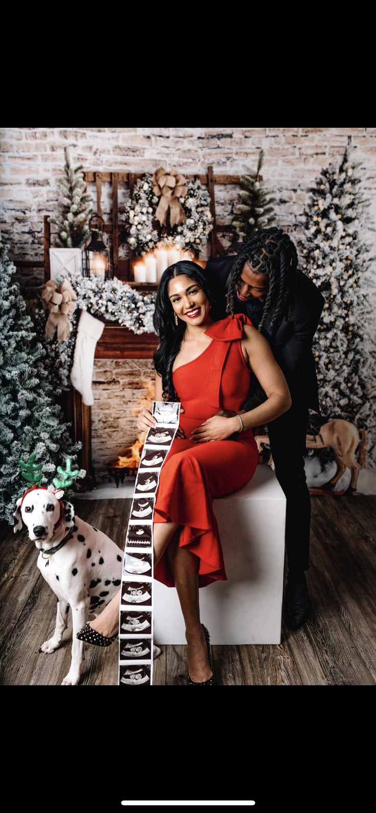 a man and woman sitting on top of a chair next to a dalmatian dog