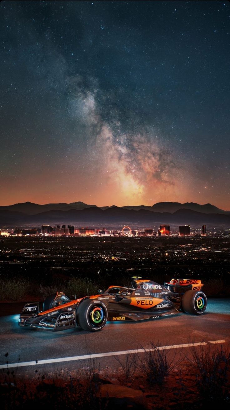 a race car driving down the road at night with stars in the sky behind it