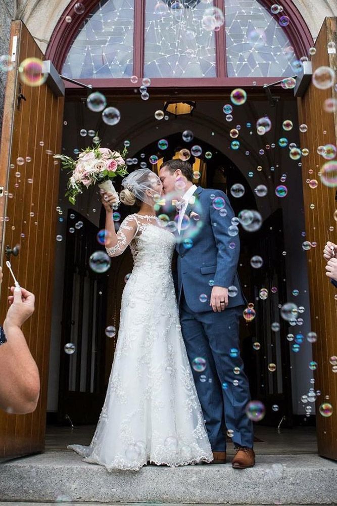 a bride and groom are kissing in front of the church door with bubbles all around them