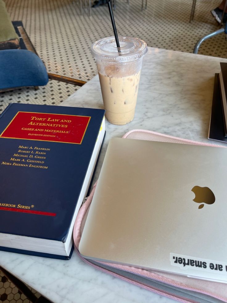 an open laptop computer sitting on top of a table next to a book and drink