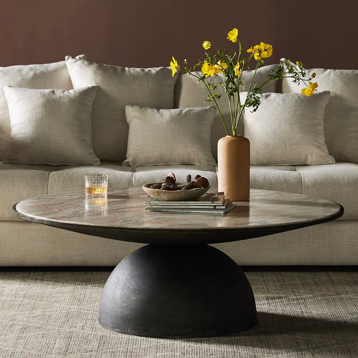 a living room with a couch, coffee table and yellow flowers in the centerpiece