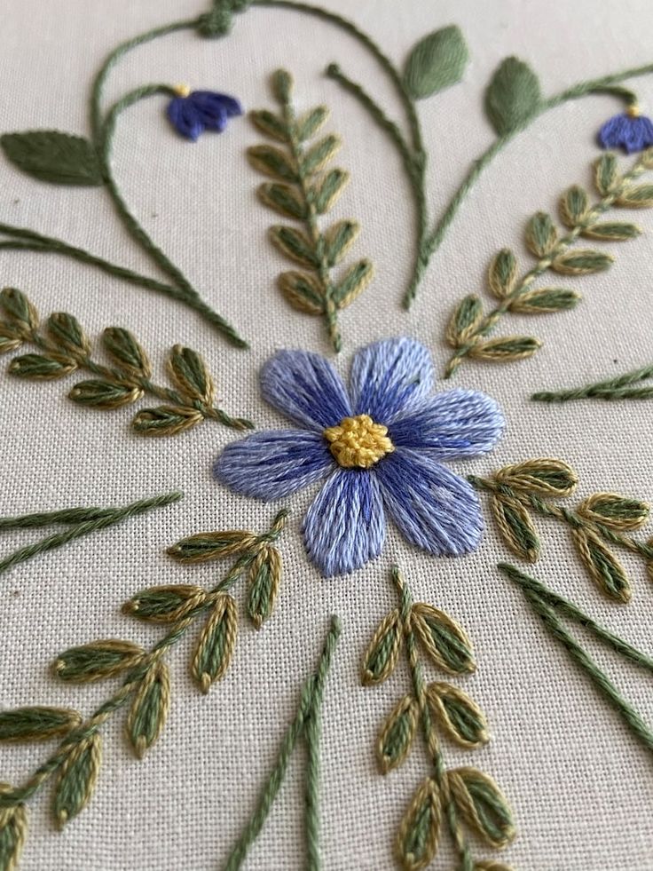 an embroidered blue flower with green leaves on it