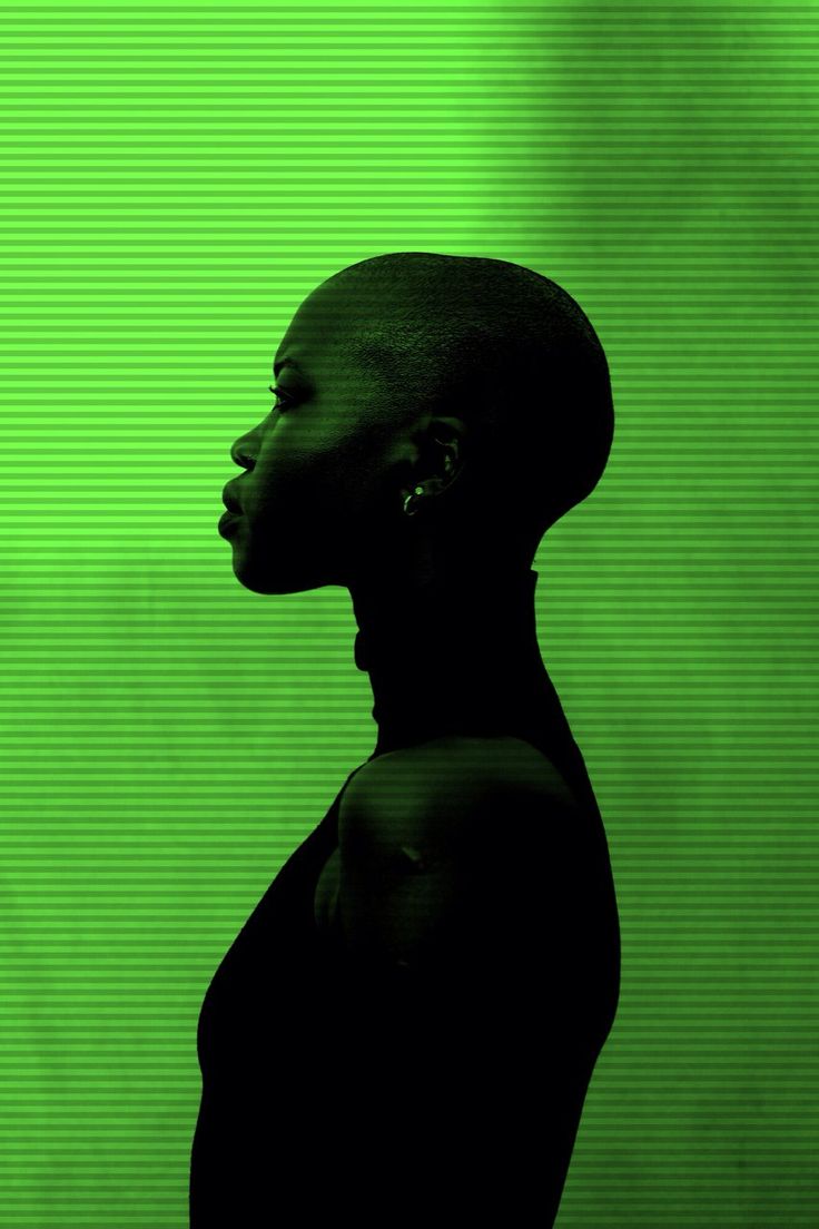 a woman standing in front of a green screen with her head turned to the side