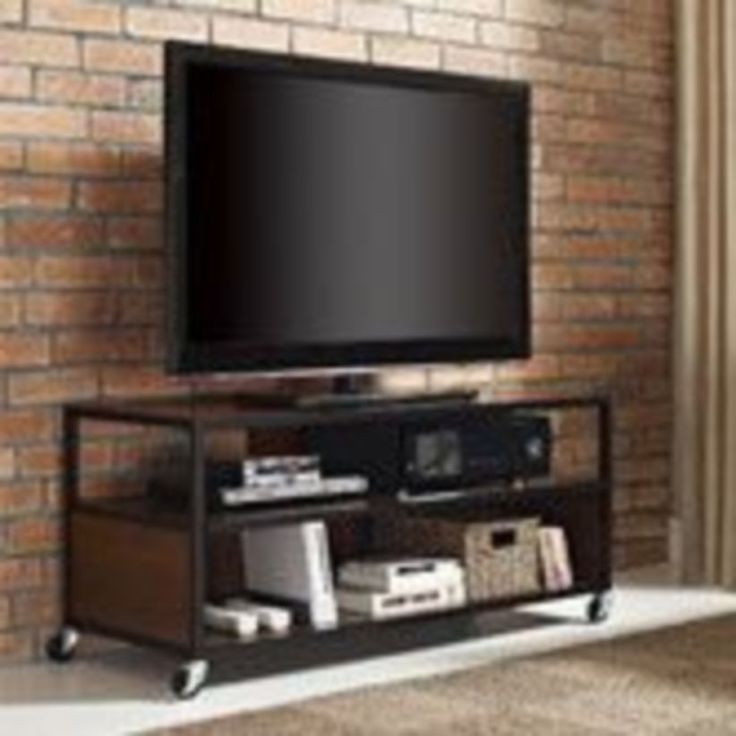 a flat screen tv sitting on top of a wooden entertainment center next to a brick wall