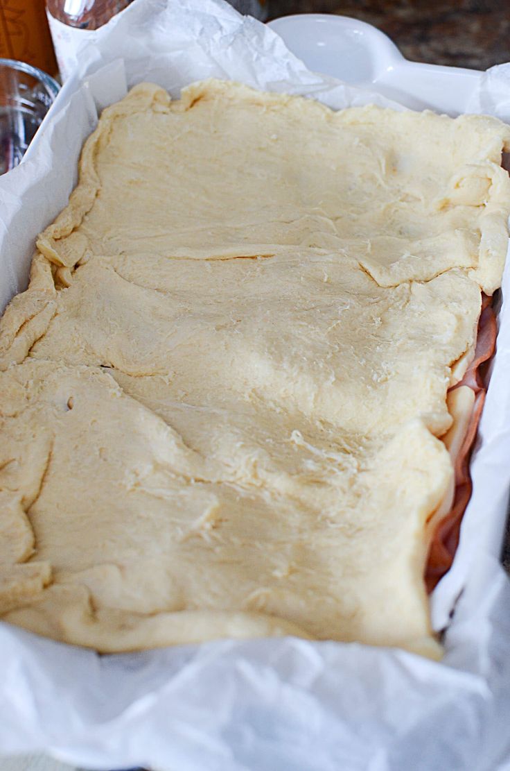 an uncooked pizza sitting on top of a white paper wrapper in a pan