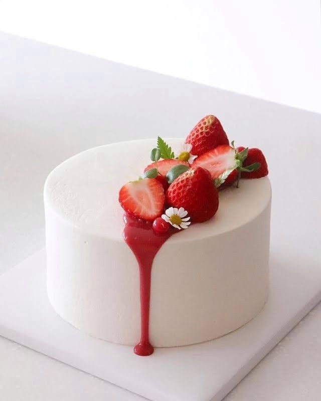 a white cake with strawberries and syrup on top