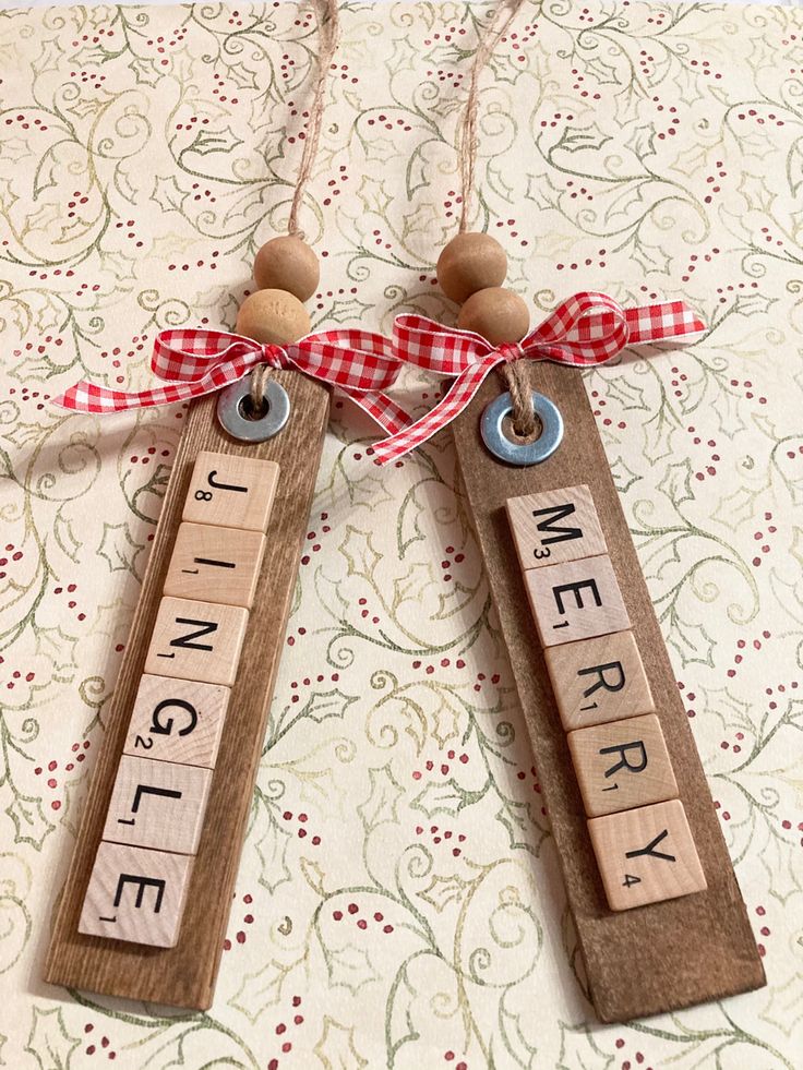 two wooden scrabbles with words on them are hanging from a red ribbon