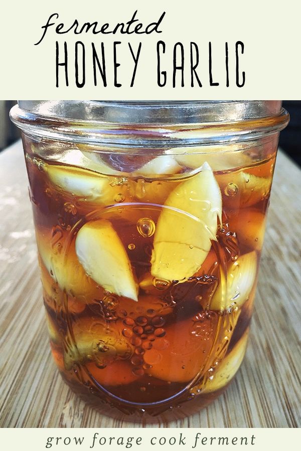 a mason jar filled with honey garlic and sliced apples on top of a wooden table