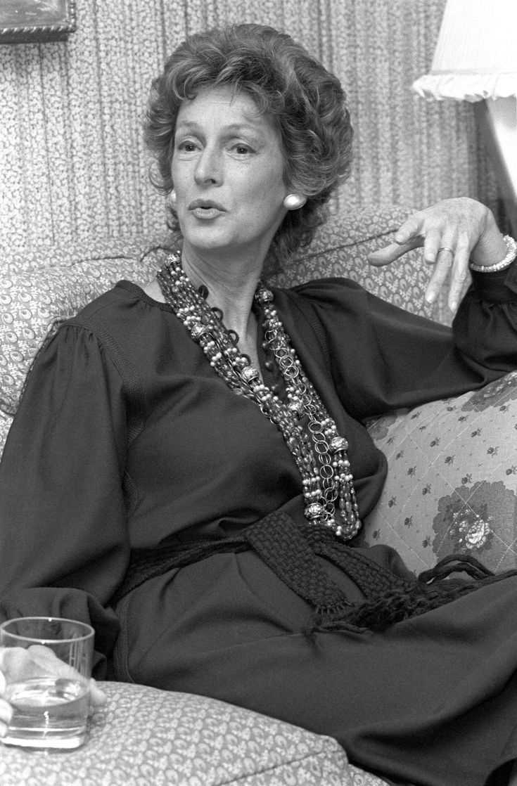 an older woman sitting on a couch with a glass of water in front of her