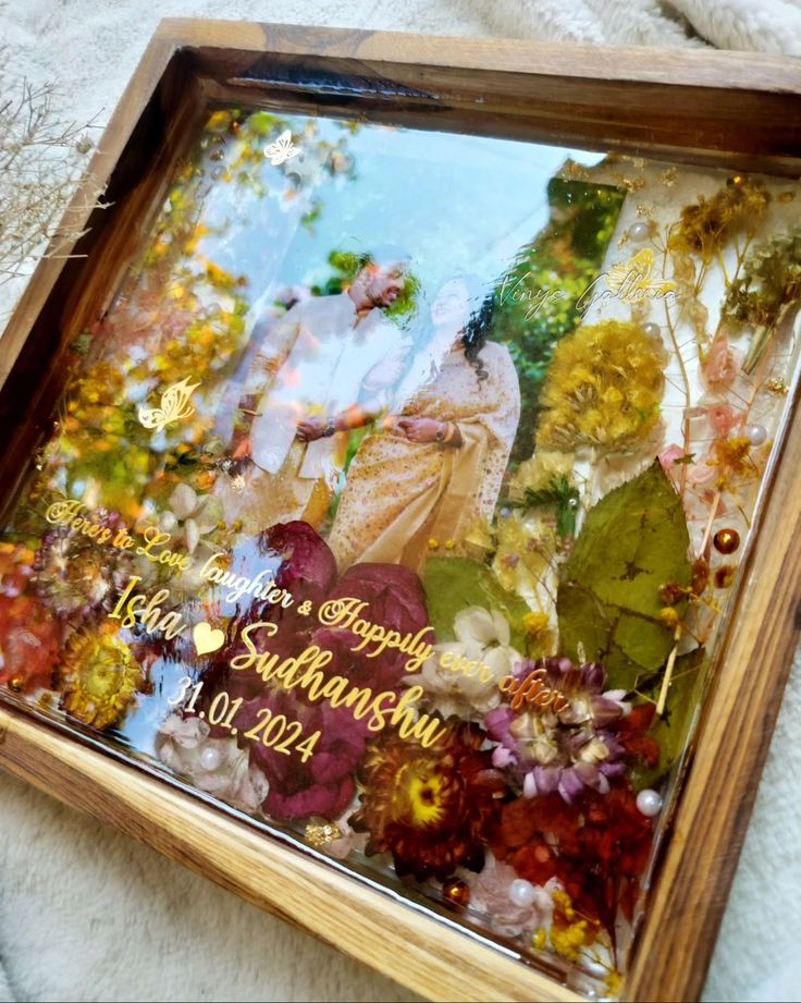 a wooden frame with an image of two people and flowers in the background on a white blanket