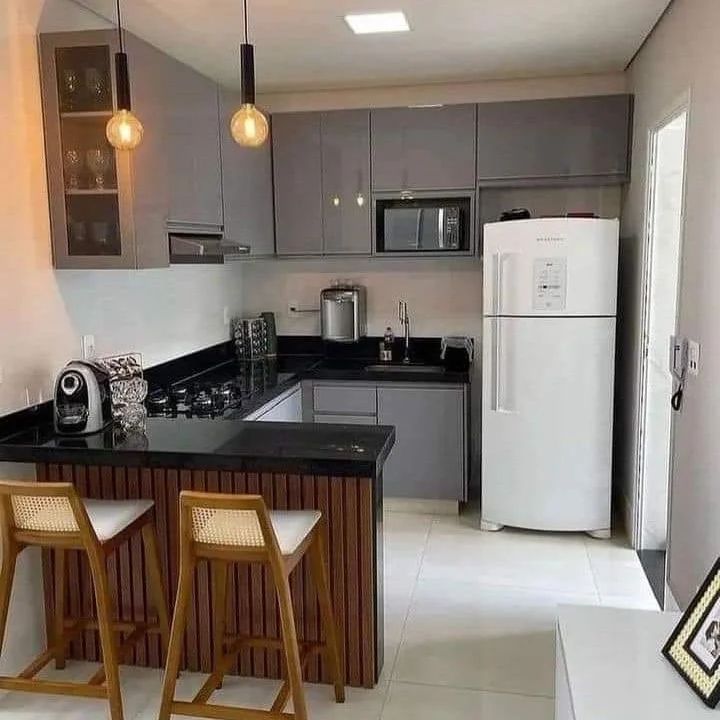 a kitchen with two bar stools next to a refrigerator and microwave in the corner