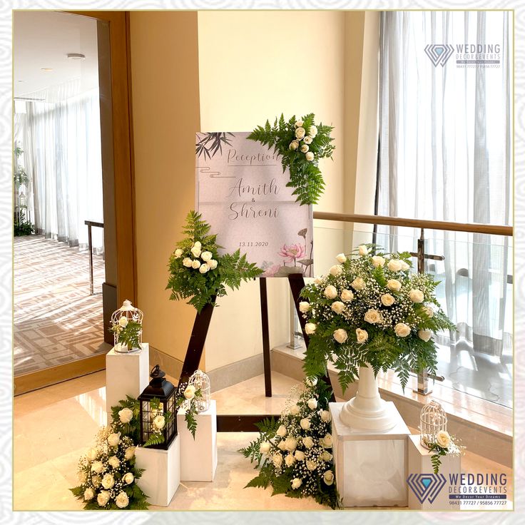 flowers and greenery on display in front of a wedding sign at the bottom of stairs