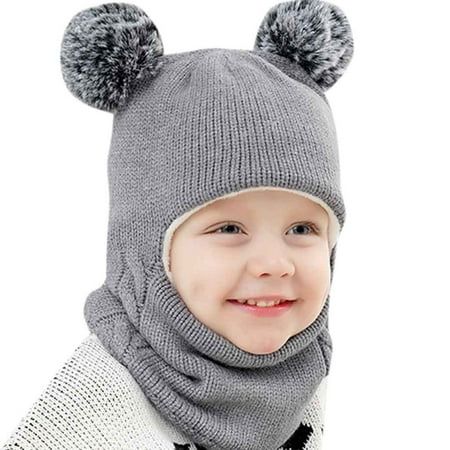 a little boy wearing a gray hat and scarf with two pompoms on it