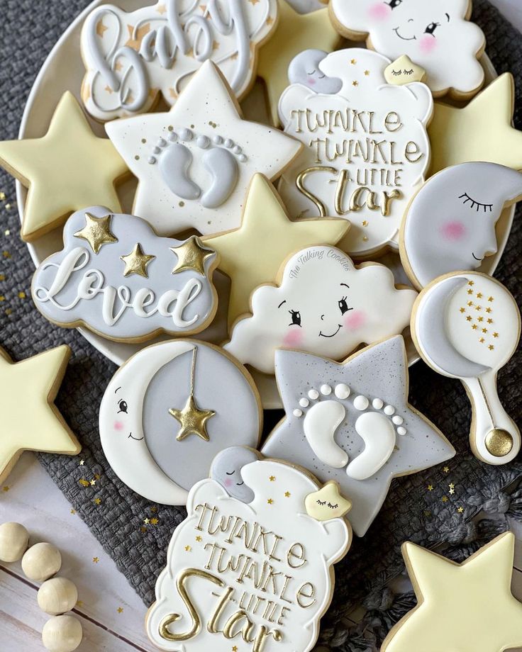 some cookies that are on a plate with stars and moon decorations in the shape of baby's feet