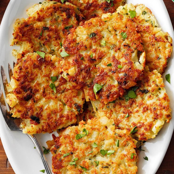 a white plate topped with crab cakes next to a fork