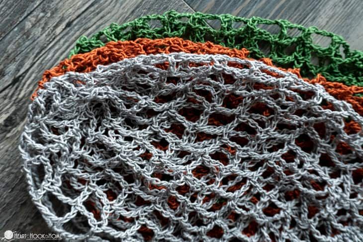 three crocheted dishcloths sitting on top of a wooden table