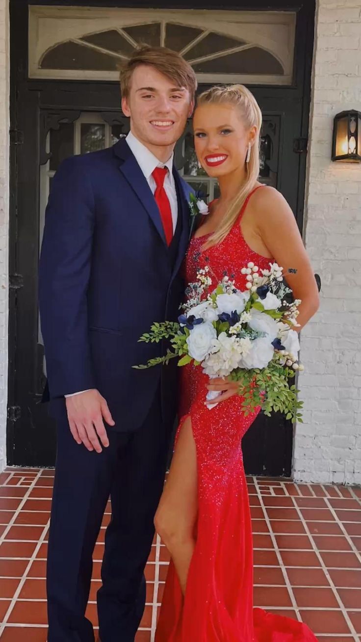 a man in a suit and tie standing next to a woman in a red dress