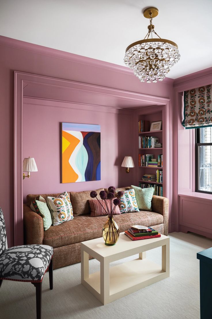 a living room with pink walls and furniture in the corner, along with a painting on the wall