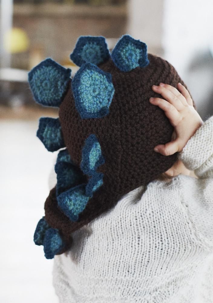 a young child wearing a knitted hat with blue flowers on the front and back