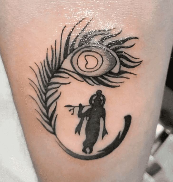 a black and white photo of a person with a peacock tattoo on their leg, next to an eye